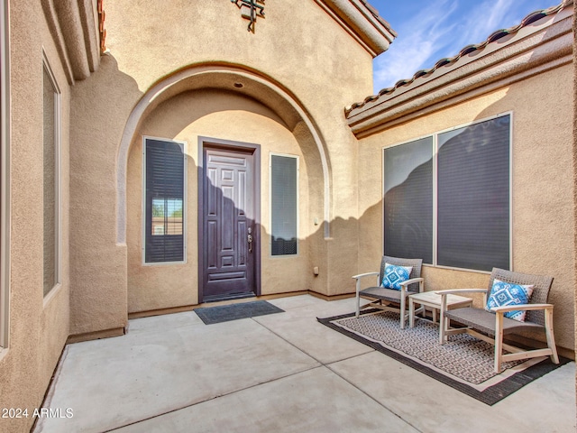 entrance to property with a tiled roof, a patio area, and stucco siding