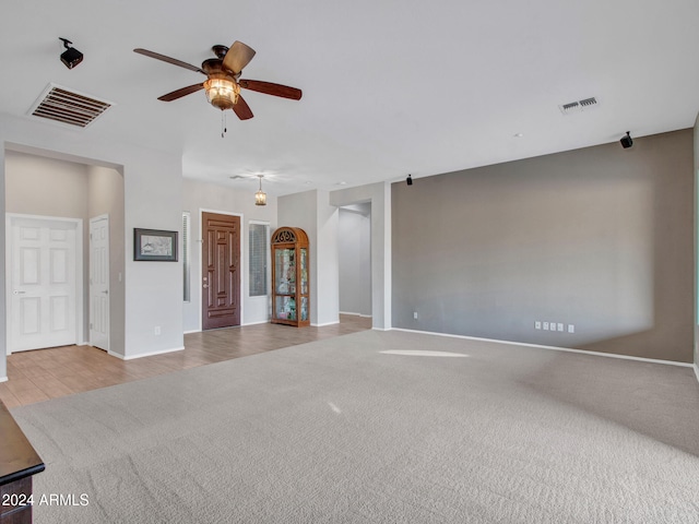 unfurnished room featuring ceiling fan, wood finished floors, carpet flooring, and visible vents