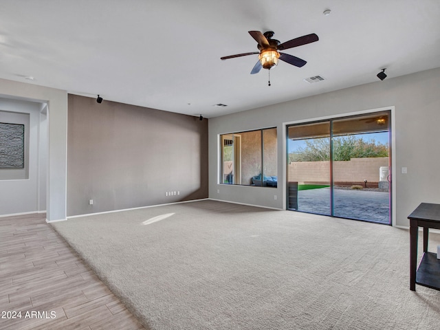 unfurnished living room with baseboards, visible vents, a ceiling fan, and light colored carpet