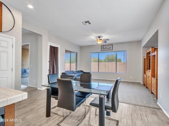 dining room with ceiling fan, light wood-type flooring, visible vents, and baseboards