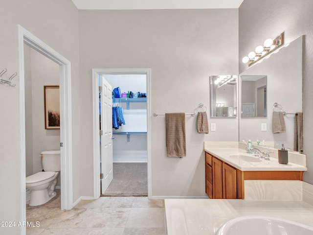 full bathroom featuring toilet, a walk in closet, vanity, and baseboards