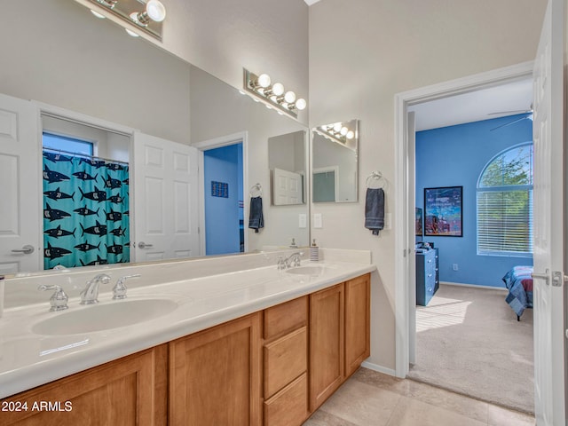 ensuite bathroom featuring double vanity, baseboards, a sink, and tile patterned floors