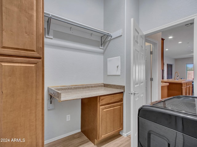 interior space featuring laundry area, a sink, visible vents, baseboards, and light wood-style floors