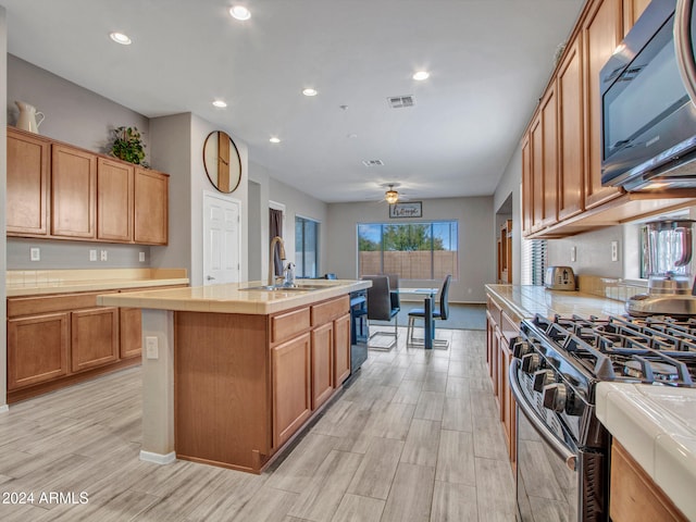 kitchen featuring sink, a kitchen island with sink, appliances with stainless steel finishes, and light hardwood / wood-style flooring