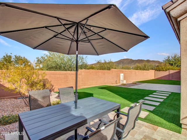 view of patio with outdoor dining area, a fenced backyard, and a mountain view