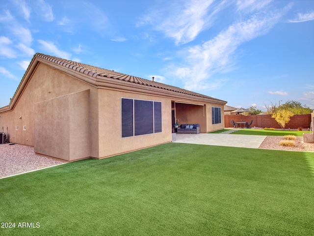 rear view of house featuring a patio, a tiled roof, fence, a yard, and stucco siding