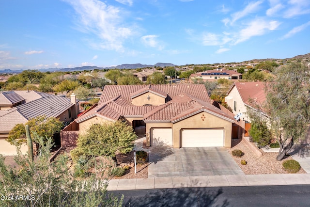 view of front of home featuring a garage, driveway, a tile roof, a mountain view, and stucco siding