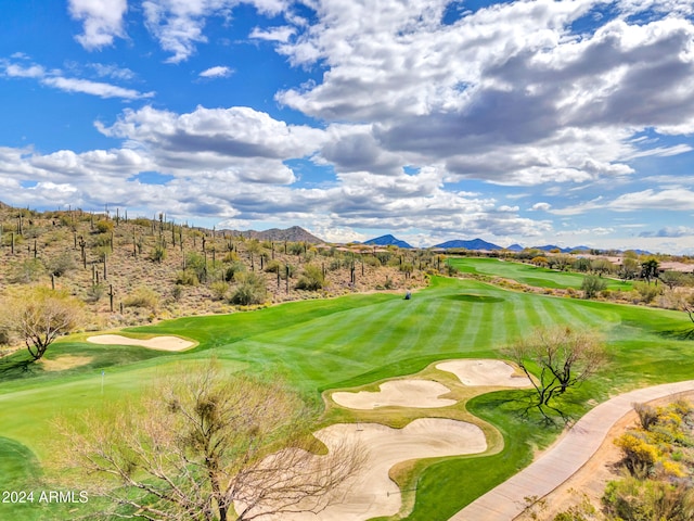 view of community featuring view of golf course, a mountain view, and a lawn