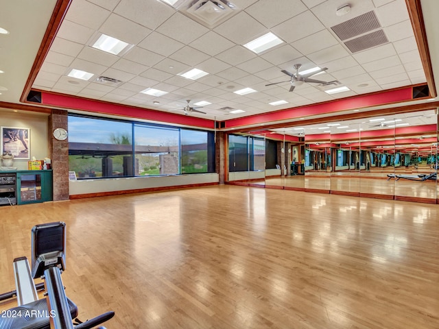 workout area featuring a paneled ceiling, ceiling fan, and wood-type flooring