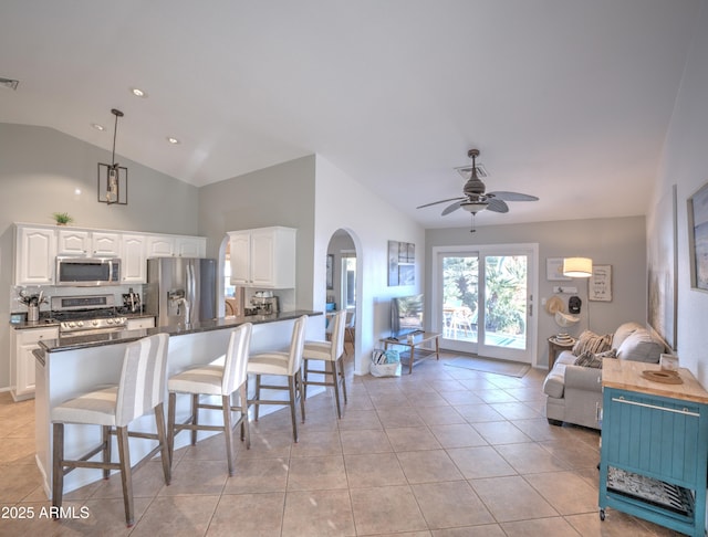 kitchen with lofted ceiling, light tile patterned floors, hanging light fixtures, stainless steel appliances, and white cabinets