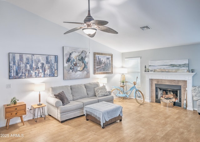 living room with vaulted ceiling, ceiling fan, a fireplace, and light wood-type flooring