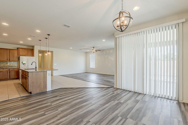 27413 W Tonopah Dr, Buckeye, AZ 85396 - kitchen featuring brown cabinets, light wood-style floors, light stone countertops, decorative light fixtures, and a chandelier