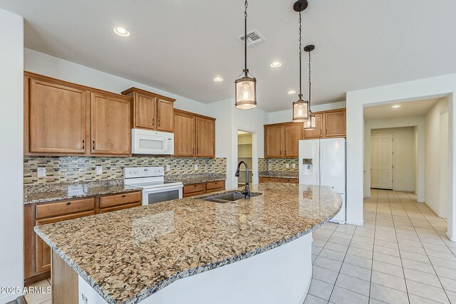 27413 W Tonopah Dr, Buckeye, AZ 85396 - kitchen with white appliances, a sink, brown cabinetry, an island with sink, and backsplash