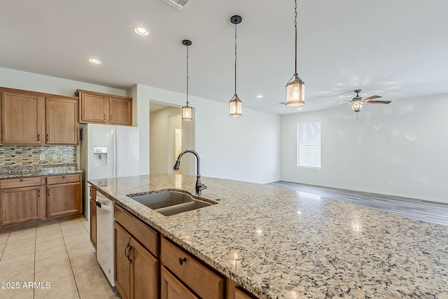 27413 W Tonopah Dr, Buckeye, AZ 85396 - kitchen with a sink, ceiling fan, dishwashing machine, brown cabinets, and decorative backsplash