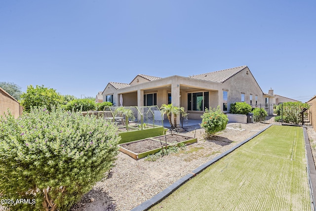 27413 W Tonopah Dr, Buckeye, AZ 85396 - rear view of property featuring fence, a garden, stucco siding, and a tile roof