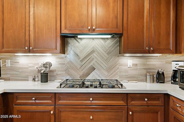 3801 N Goldwater Blvd Unit 201, Scottsdale, AZ 85251 - kitchen with decorative backsplash, gas stovetop, light countertops, and brown cabinets