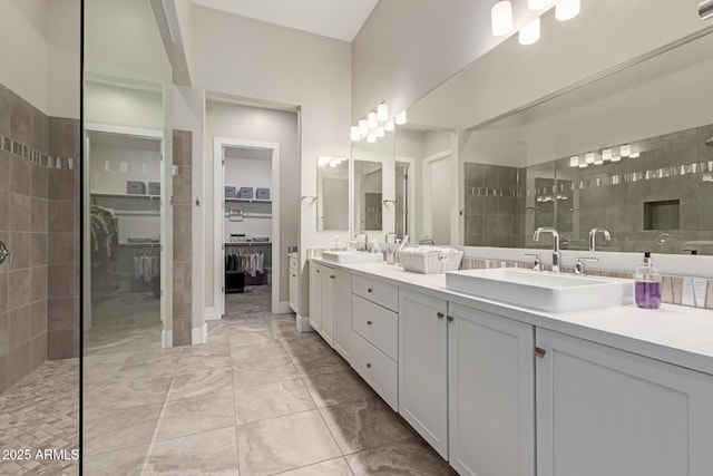 bathroom featuring double vanity, a walk in closet, walk in shower, and a sink