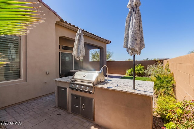 view of patio / terrace featuring grilling area, an outdoor kitchen, and a fenced backyard