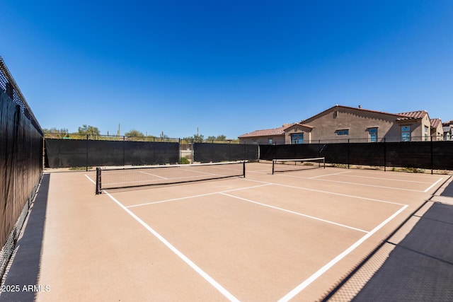 view of tennis court with community basketball court and fence