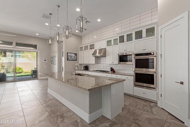 kitchen featuring a sink, decorative backsplash, stainless steel appliances, white cabinets, and under cabinet range hood