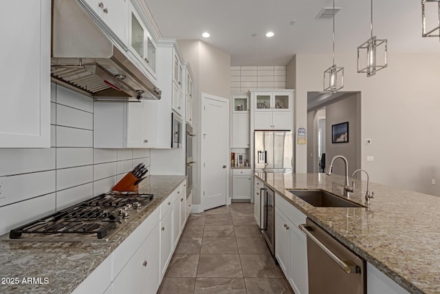 kitchen featuring visible vents, a sink, decorative backsplash, under cabinet range hood, and appliances with stainless steel finishes