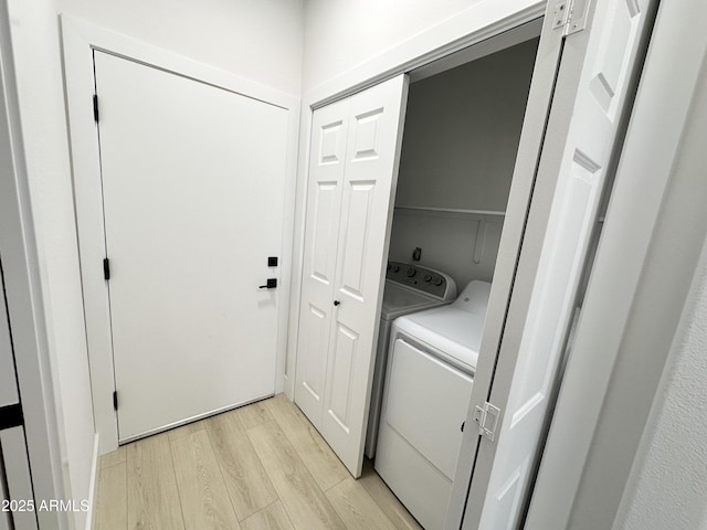 clothes washing area featuring washing machine and clothes dryer, light wood finished floors, and laundry area