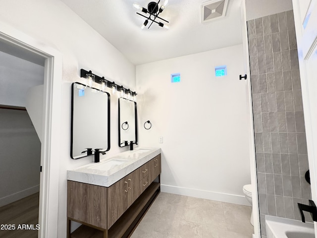 bathroom with a sink, double vanity, toilet, and baseboards