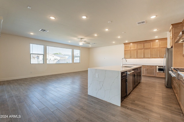 kitchen featuring ceiling fan, sink, dark hardwood / wood-style flooring, an island with sink, and appliances with stainless steel finishes