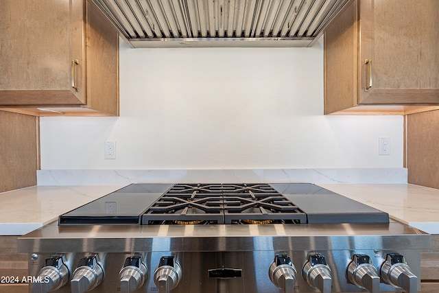 kitchen featuring light stone counters, wall chimney exhaust hood, and stainless steel stove