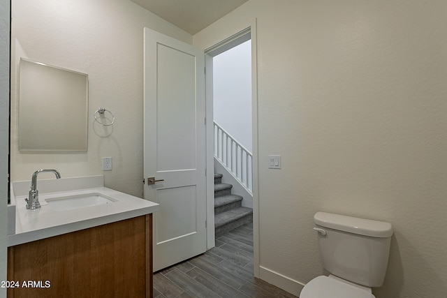 bathroom featuring toilet, vanity, and hardwood / wood-style flooring