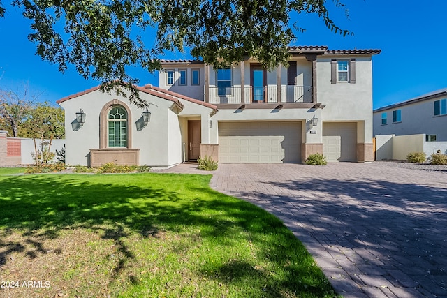 mediterranean / spanish house with a garage, a balcony, and a front lawn