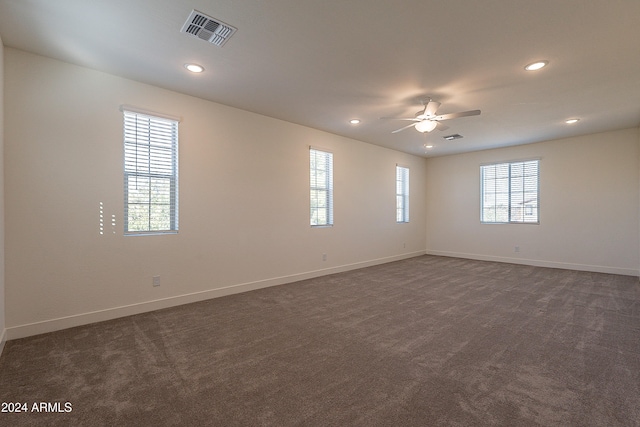 unfurnished room with ceiling fan and dark colored carpet