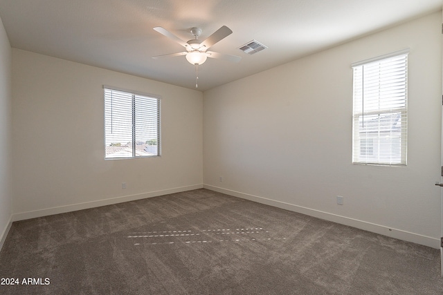 unfurnished room featuring ceiling fan, plenty of natural light, and dark colored carpet