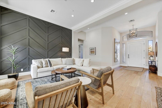 living room with light wood-type flooring and crown molding