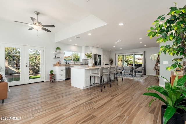 kitchen featuring ceiling fan, a kitchen island, white cabinetry, and stainless steel appliances