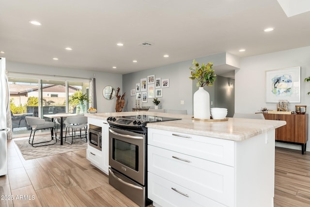 kitchen featuring stainless steel appliances, a center island, white cabinets, and light stone countertops