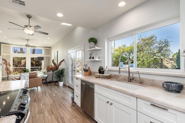 kitchen featuring appliances with stainless steel finishes, light wood-type flooring, white cabinets, light stone counters, and sink