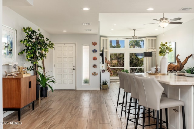 kitchen with a breakfast bar area, light hardwood / wood-style floors, and ceiling fan