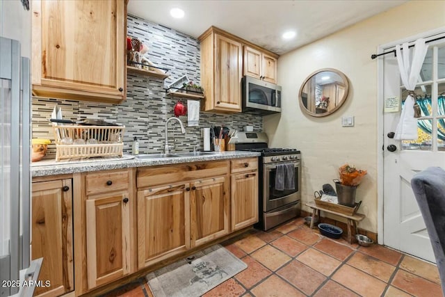 kitchen with light tile patterned floors, appliances with stainless steel finishes, sink, and backsplash