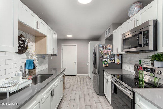 kitchen featuring tasteful backsplash, white cabinets, and appliances with stainless steel finishes