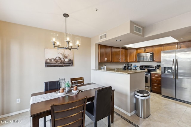 kitchen with appliances with stainless steel finishes, decorative light fixtures, light tile patterned floors, kitchen peninsula, and light stone countertops