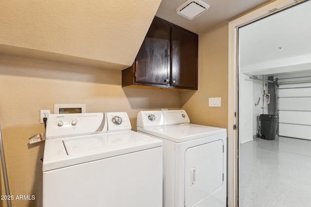 clothes washing area with cabinets and washer and clothes dryer