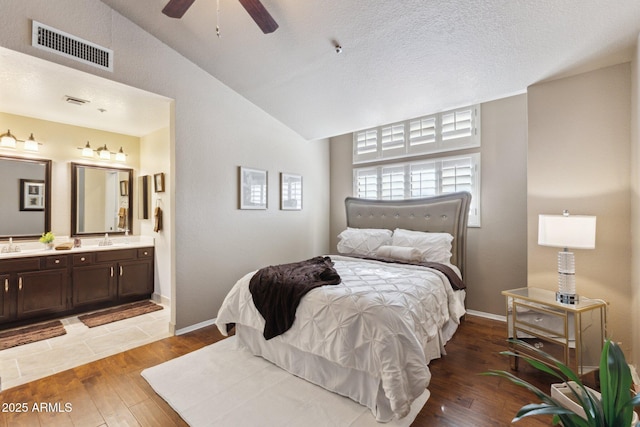 bedroom featuring ensuite bathroom, sink, wood-type flooring, vaulted ceiling, and ceiling fan