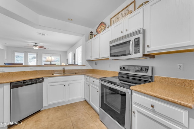 kitchen with sink, light tile patterned flooring, white cabinets, and appliances with stainless steel finishes