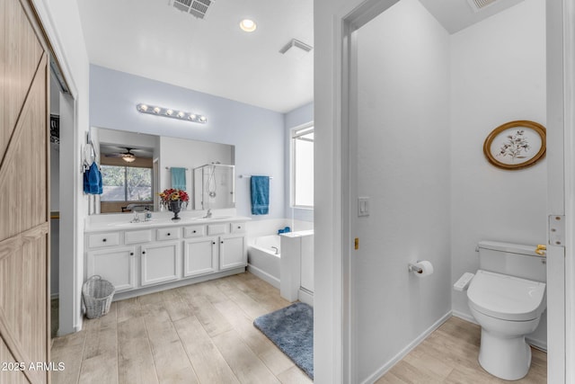 bathroom featuring hardwood / wood-style flooring, vanity, a bath, and toilet