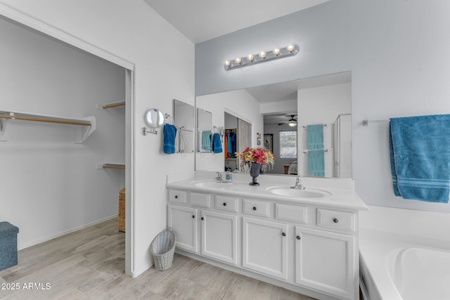 bathroom with ceiling fan, a tub to relax in, wood-type flooring, and vanity