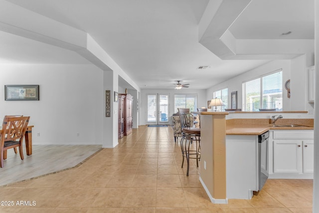 kitchen featuring sink, a breakfast bar area, white cabinets, light tile patterned flooring, and stainless steel dishwasher