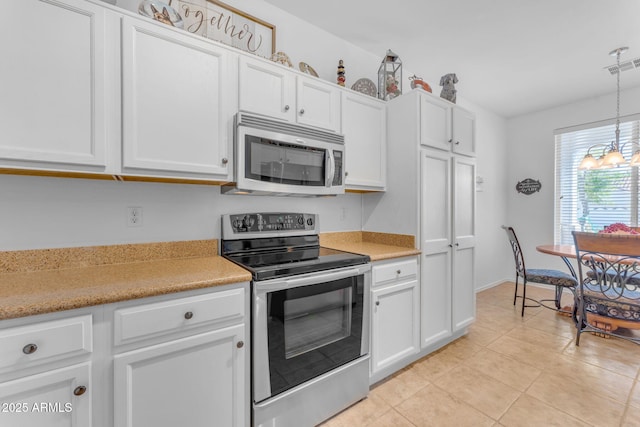 kitchen featuring light tile patterned flooring, appliances with stainless steel finishes, pendant lighting, and white cabinets