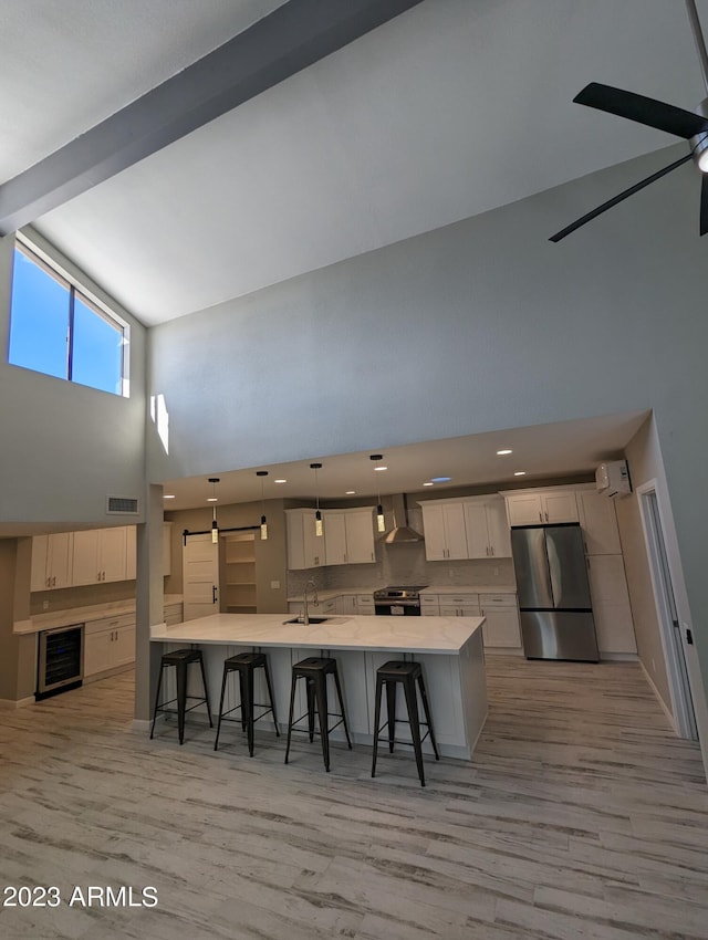 kitchen featuring ceiling fan, hanging light fixtures, light hardwood / wood-style flooring, stainless steel appliances, and high vaulted ceiling