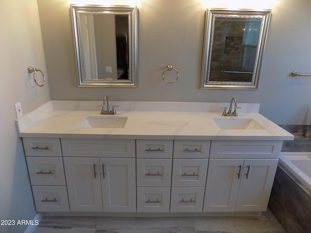 bathroom with a washtub and double vanity